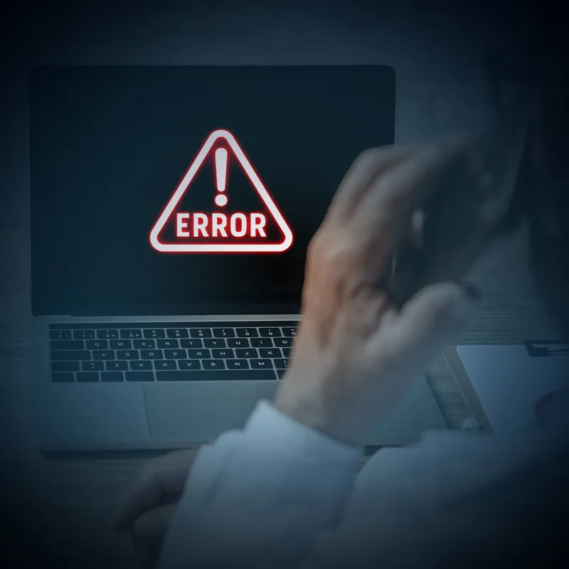 شاشة حاسب محمول تعرض مثلّث تحذير أحمر مكتوب فيه ERROR، ويد تمتدّ نحو اللوحة